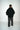 Man wearing a black hoodie and gray pants on a white background